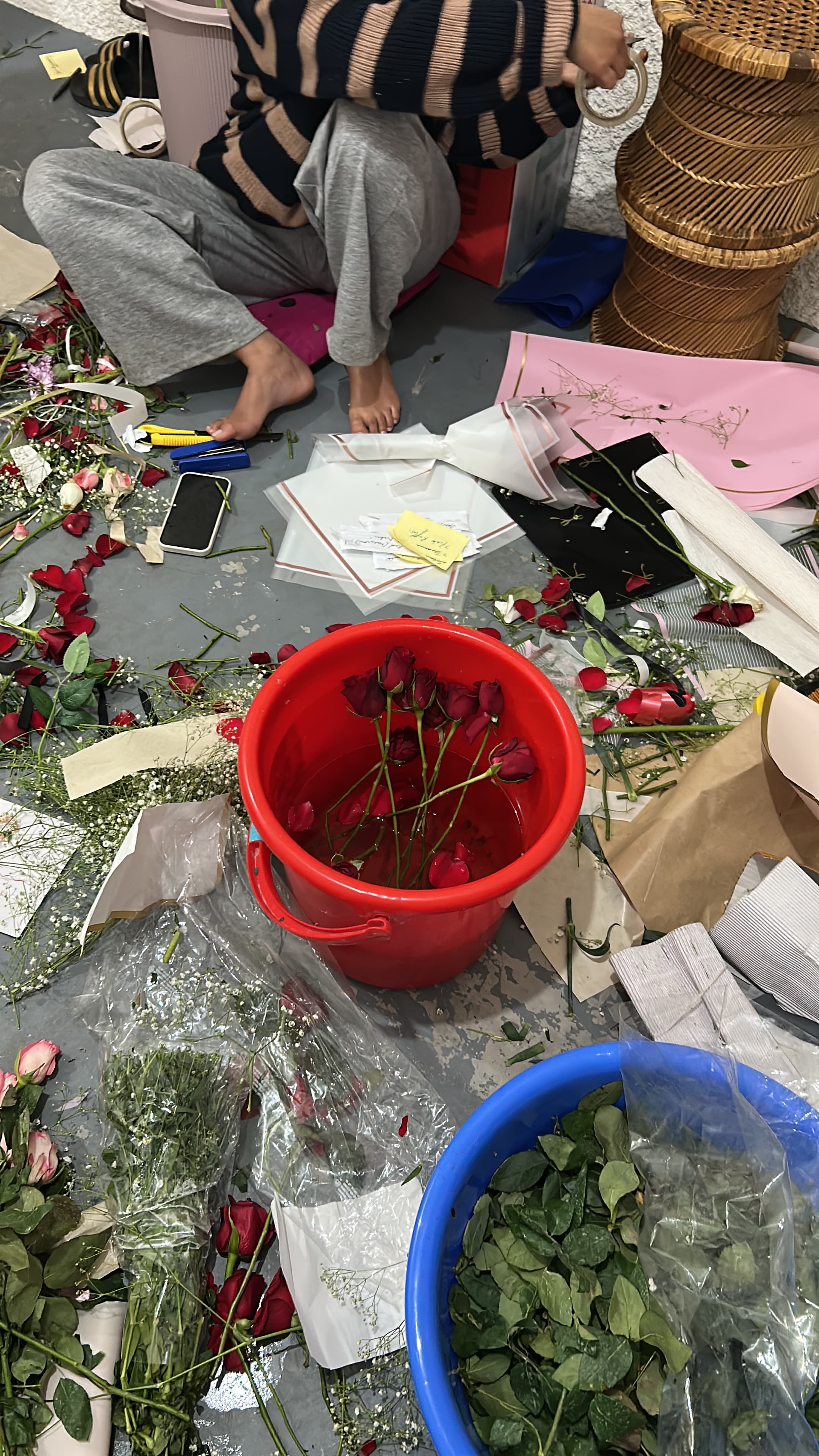 Roses, foliage and order cards laid out on the floor during a Little Token packing session.